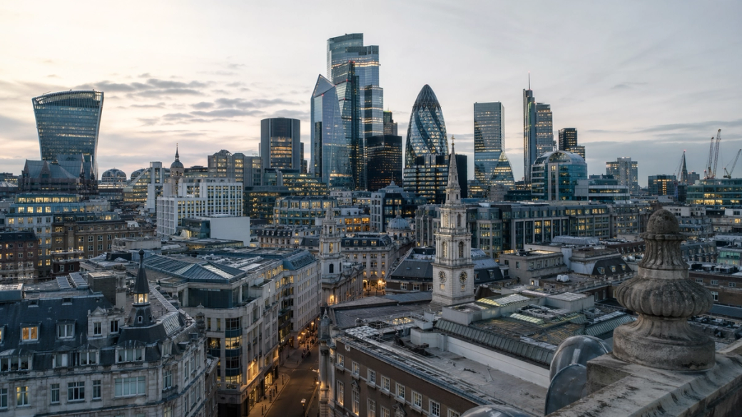 A panoramic view of London's skyline featuring a mix of modern skyscrapers and historic buildings at dusk. The image captures the contrast between the contemporary architecture and the classic structures below, showcasing the city’s dynamic urban landscape.