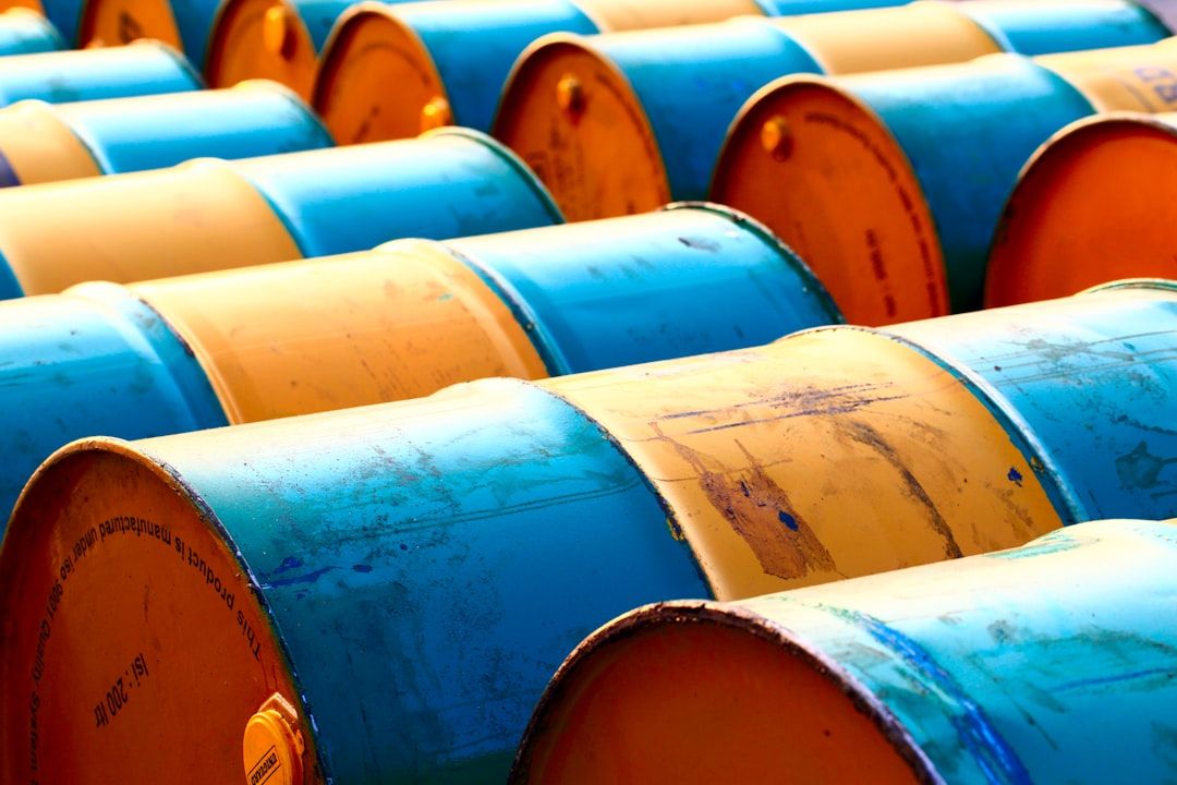 The image showcases a close-up view of numerous blue and yellow barrels arranged in rows. The barrels are cylindrical and appear to be used for storage, likely of liquids or chemicals.