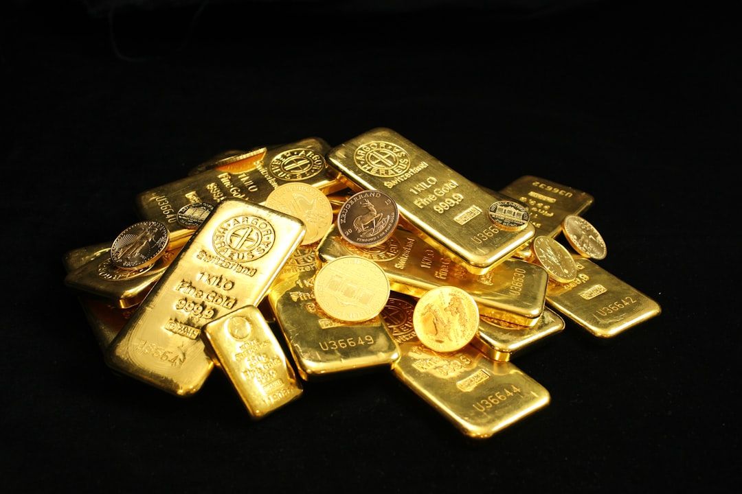 The image features a pile of gold bars and coins stacked together on a dark surface. The gold bars display various inscriptions and symbols, emphasizing their value and authenticity.