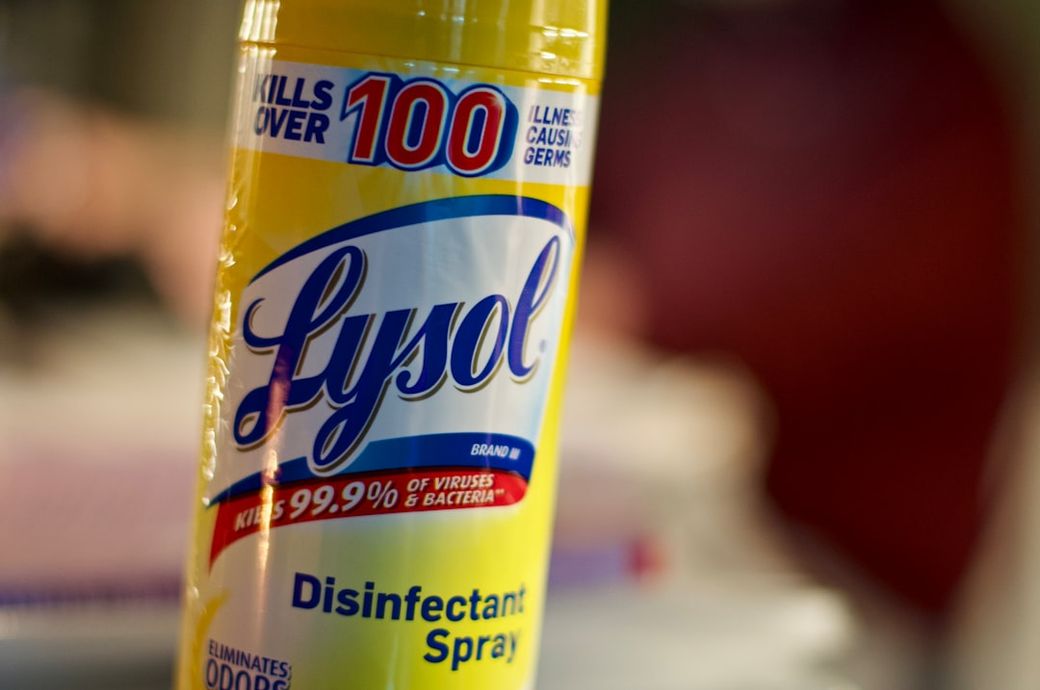 The image features a close-up of a can of Lysol disinfectant spray, highlighting its purpose of eliminating viruses and bacteria. The packaging prominently displays the brand name and product details. — Credit: Photo by Dan Dennis on Unsplash