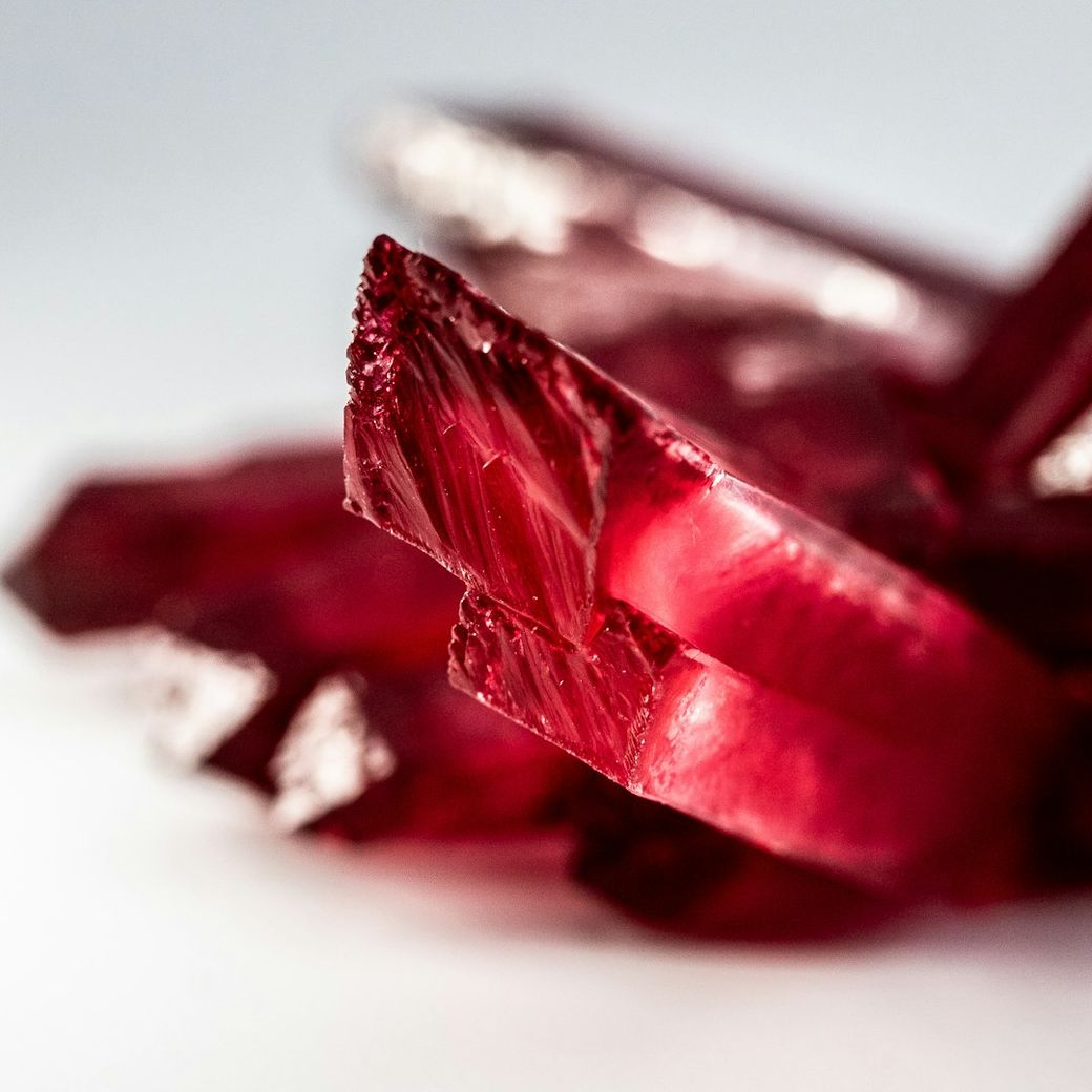 The image features a close-up view of red crystals with sharp facets and a glossy surface. The crystals are arranged in a way that highlights their intricate details and vibrant color. — Credit: Photo by Jason D on Unsplash