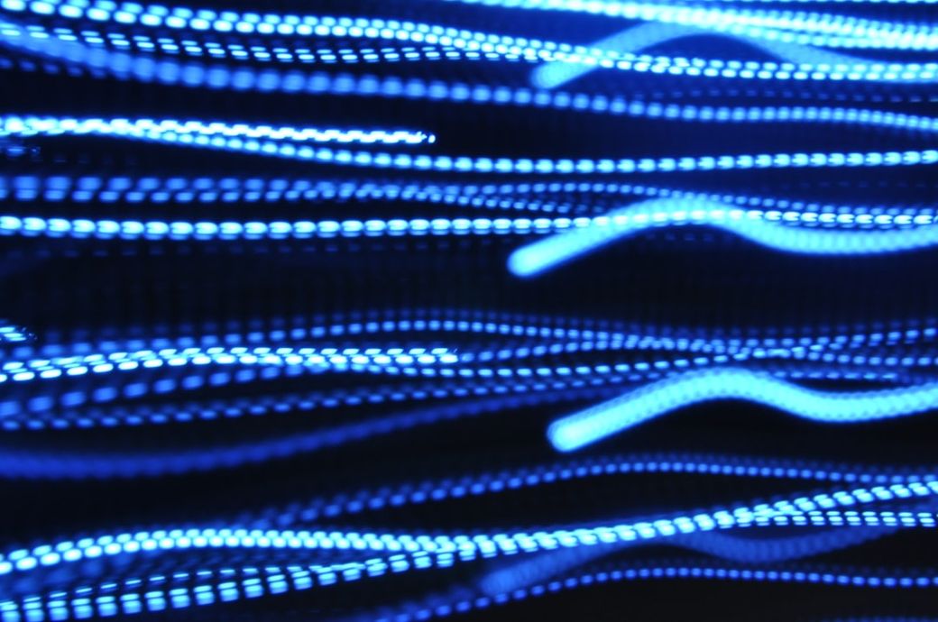 The image features a dynamic display of blue light streaks, creating a sense of motion and energy. The abstract composition suggests themes of technology and modernity. — Credit: Photo by Daniel Falcão on Unsplash