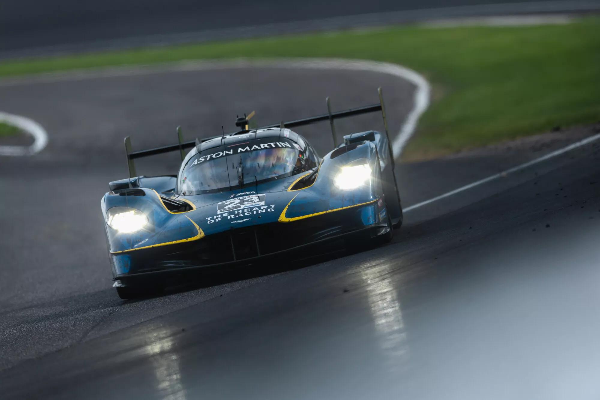 A sleek Aston Martin racing car navigates a winding track with precision. The vehicle is designed for high-speed performance, showcasing its aerodynamic features in a competitive racing environment.