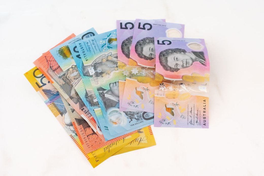 A collection of Australian banknotes stacked together on a marble surface. The notes include various denominations, showcasing the colorful designs and features unique to Australia's currency. — Credit: Photo by Melissa Walker Horn on Unsplash