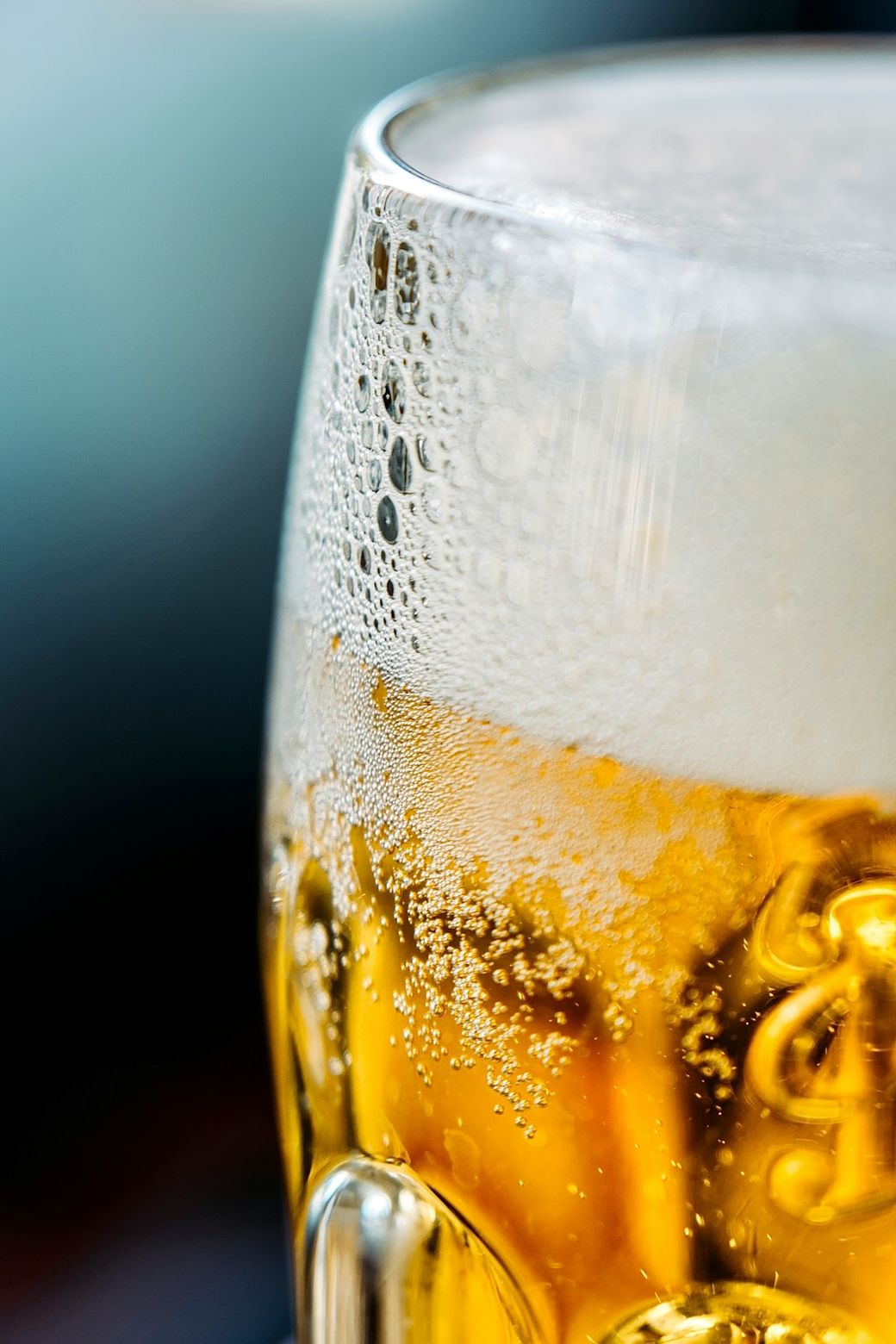 A close-up image of a frosty beer glass filled with golden liquid and topped with a creamy white froth. The condensation on the glass highlights the coldness of the beverage, creating an inviting appearance. — Credit: Photo by Tetiana Padurets on Unsplash