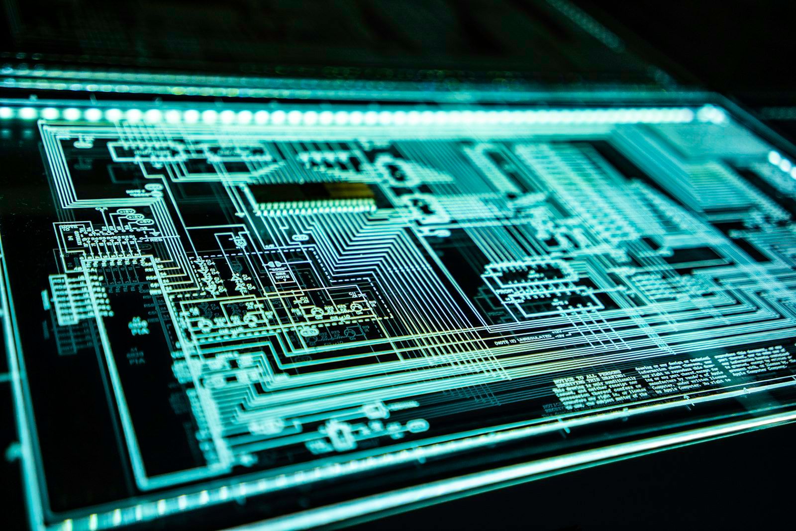 The image features a close-up view of a printed circuit board with intricate circuit paths and connections illuminated by a neon glow. This high-tech visual emphasizes the complexity of electronic design.