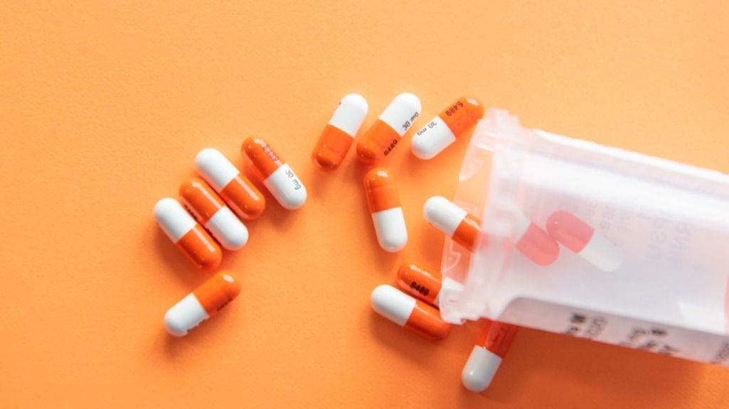 Prescription drugs on an orange background with a pill bottle. Orange pills.