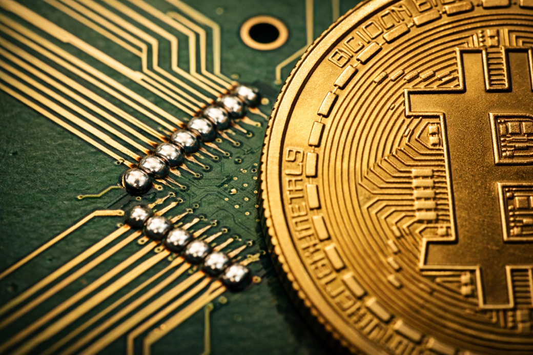 The image features a close-up of a golden Bitcoin superimposed on a green circuit board background. The intricate details of the circuit board and the Bitcoin symbol highlight the intersection of cryptocurrency and technology.