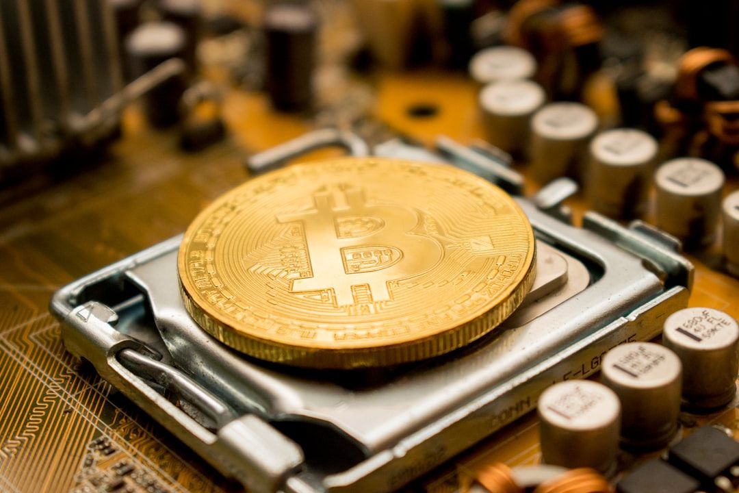 The image showcases a close-up of a golden Bitcoin coin resting on a computer circuit board. The intricate details of the electronic components surrounding the cryptocurrency highlight its technological foundation.