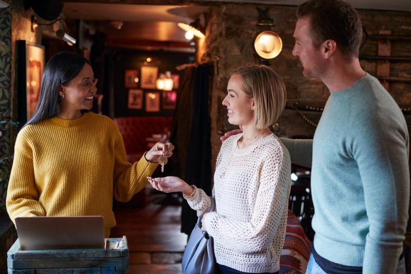 Hotellvert som ønsker gjester velkommen og overleverer nøkkel, et øyeblikk som bygger trygghet og tillit i gjestens opplevelse.