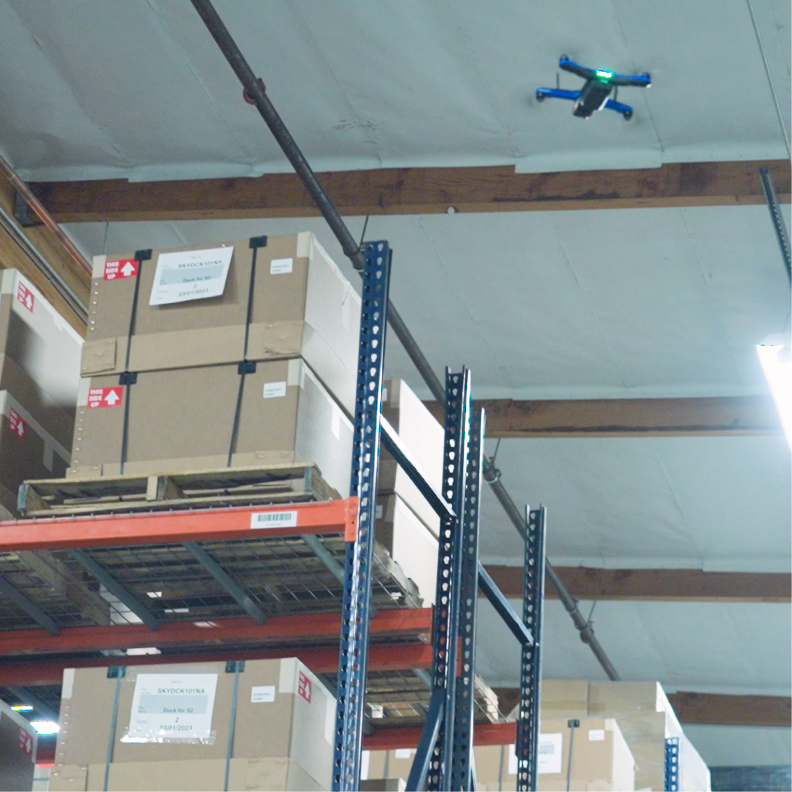 Skydio drone in flight scanning warehouse inventory above shelves