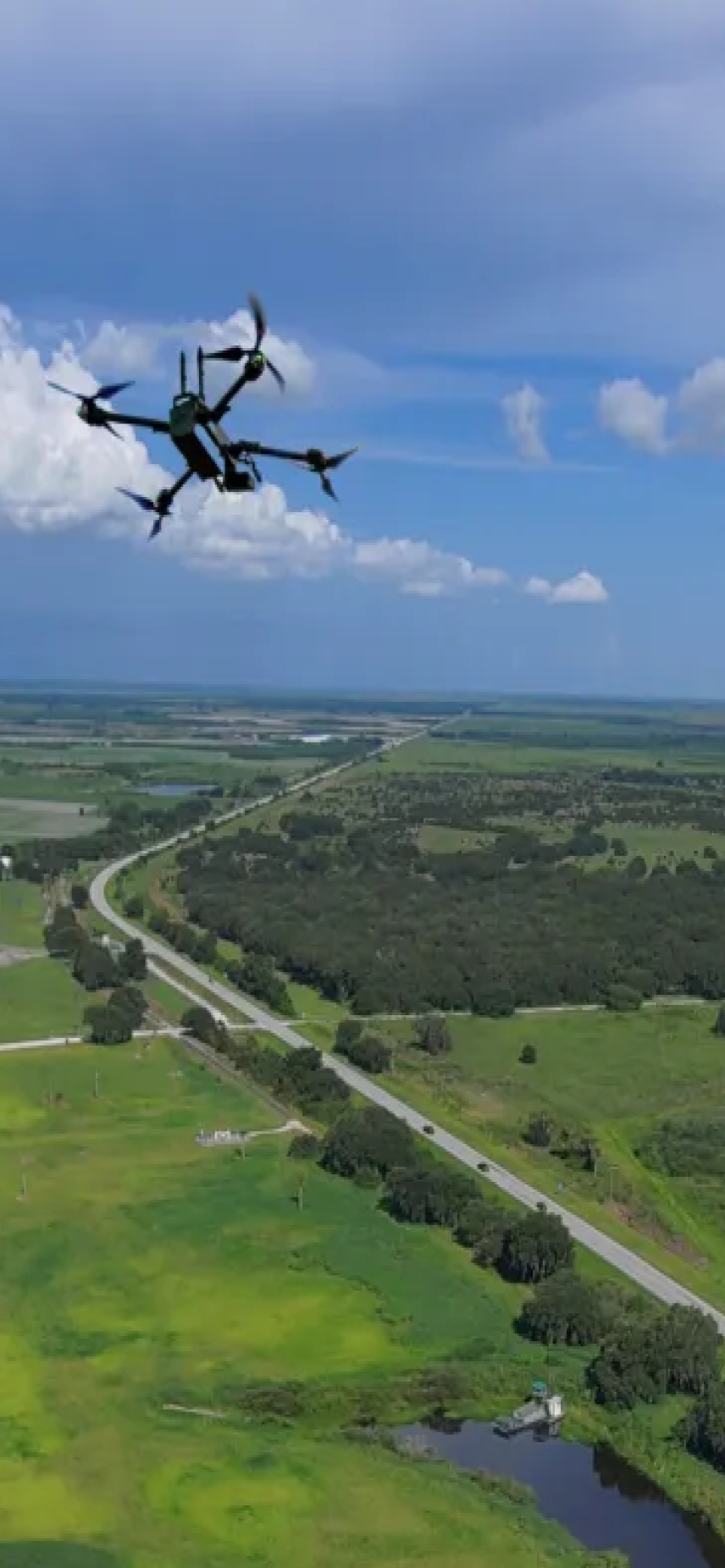 Drone in flight over rural stretch of highway portrait view