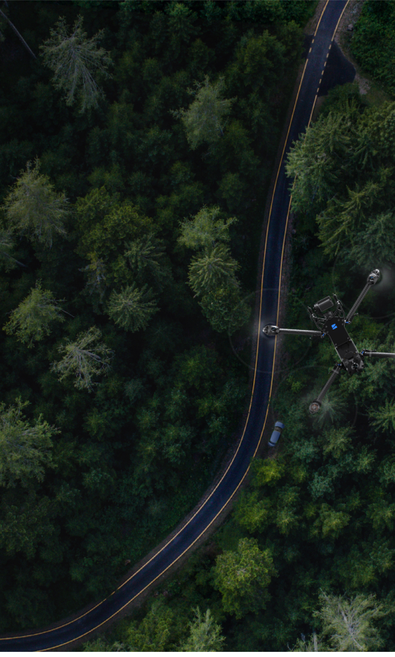 Portrait view of a Skydio drone flying above remote rural forested location