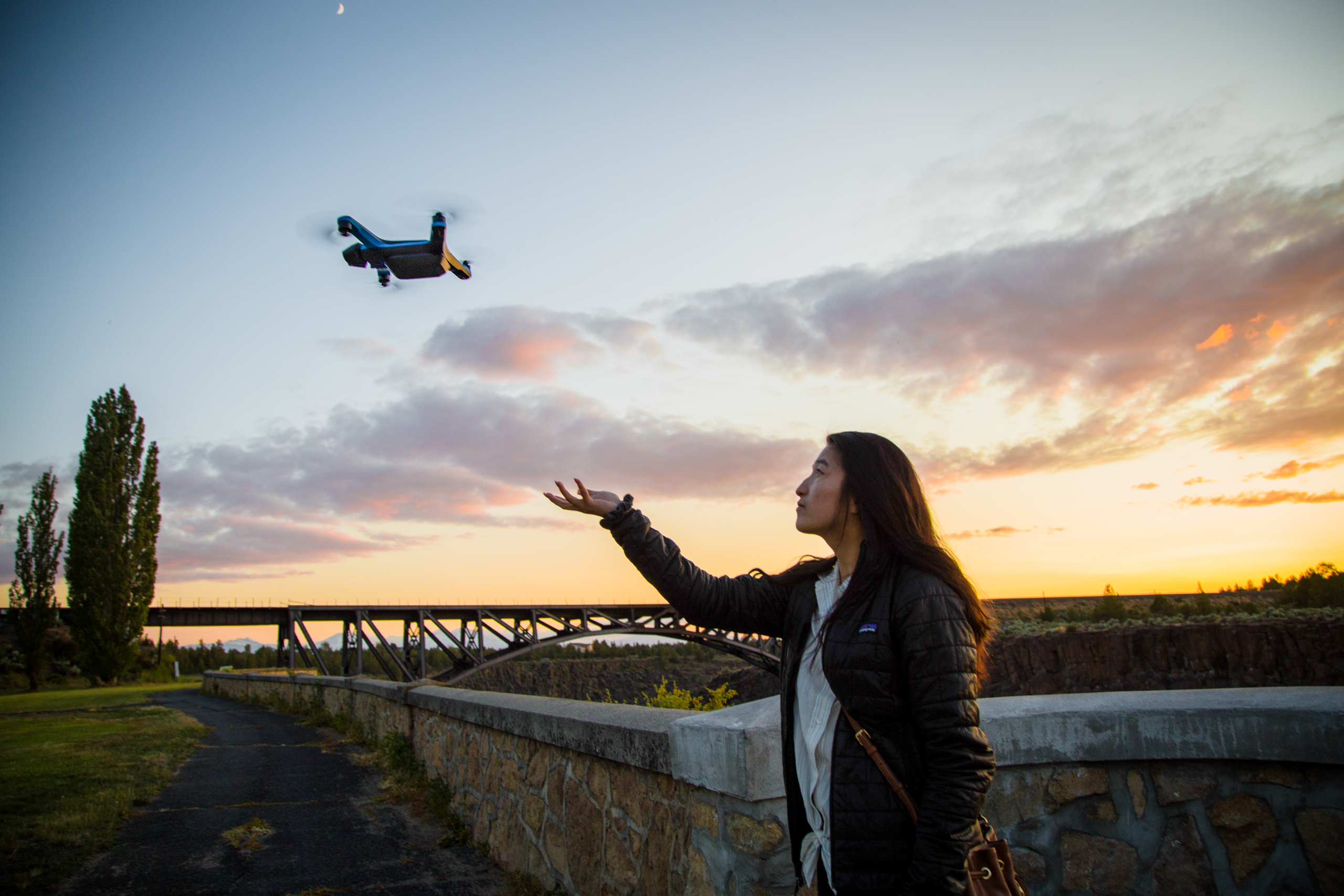 person hand launching skydio 2+ drone with colorful sunset in the background 