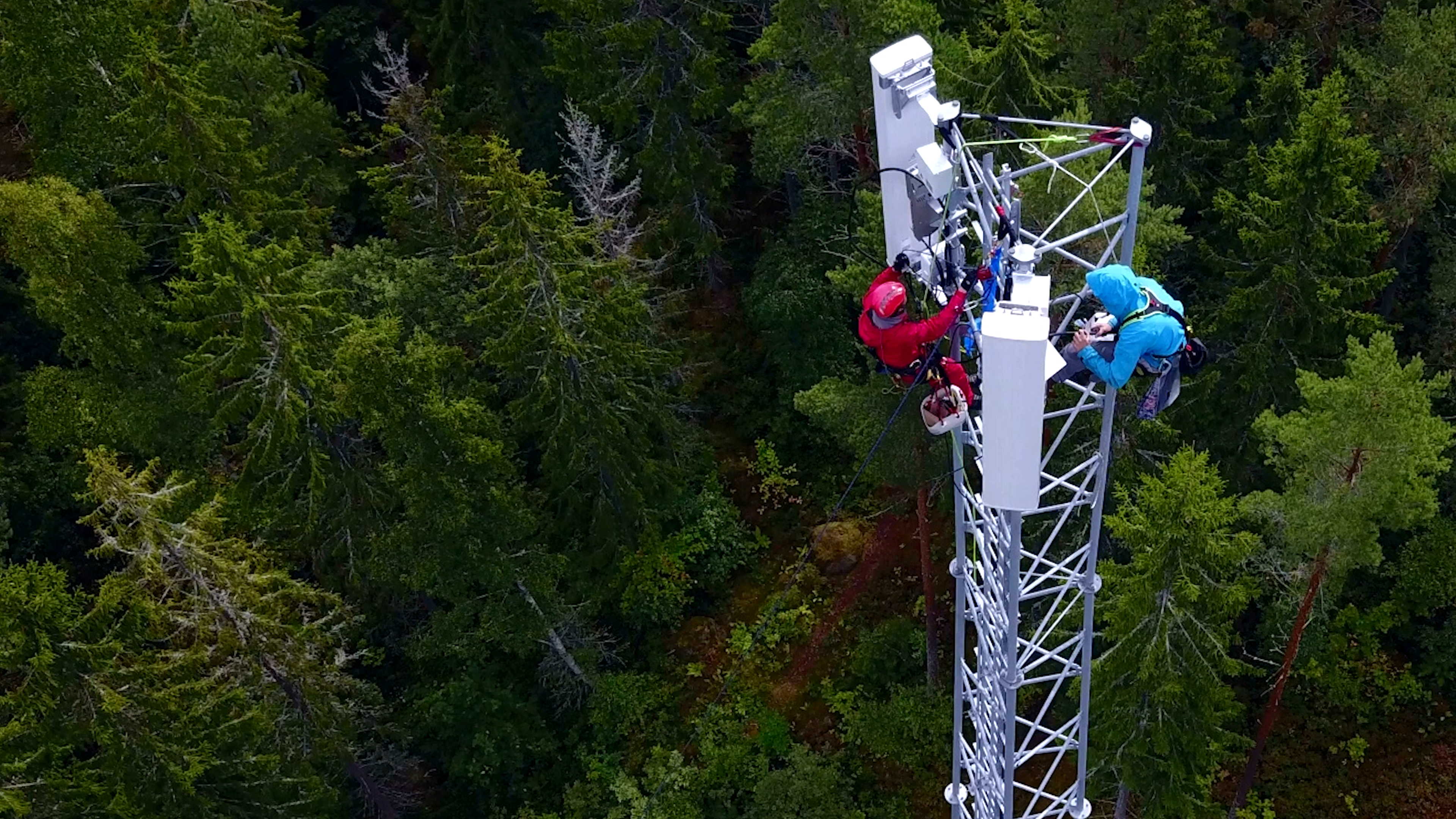 Two climbers climbing on top of a cell tower