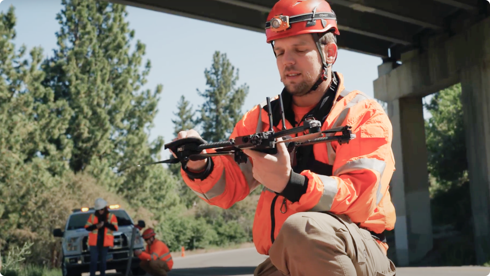 operator with a Skydio drone in hand preparing for flight with 2 others and a truck in the background