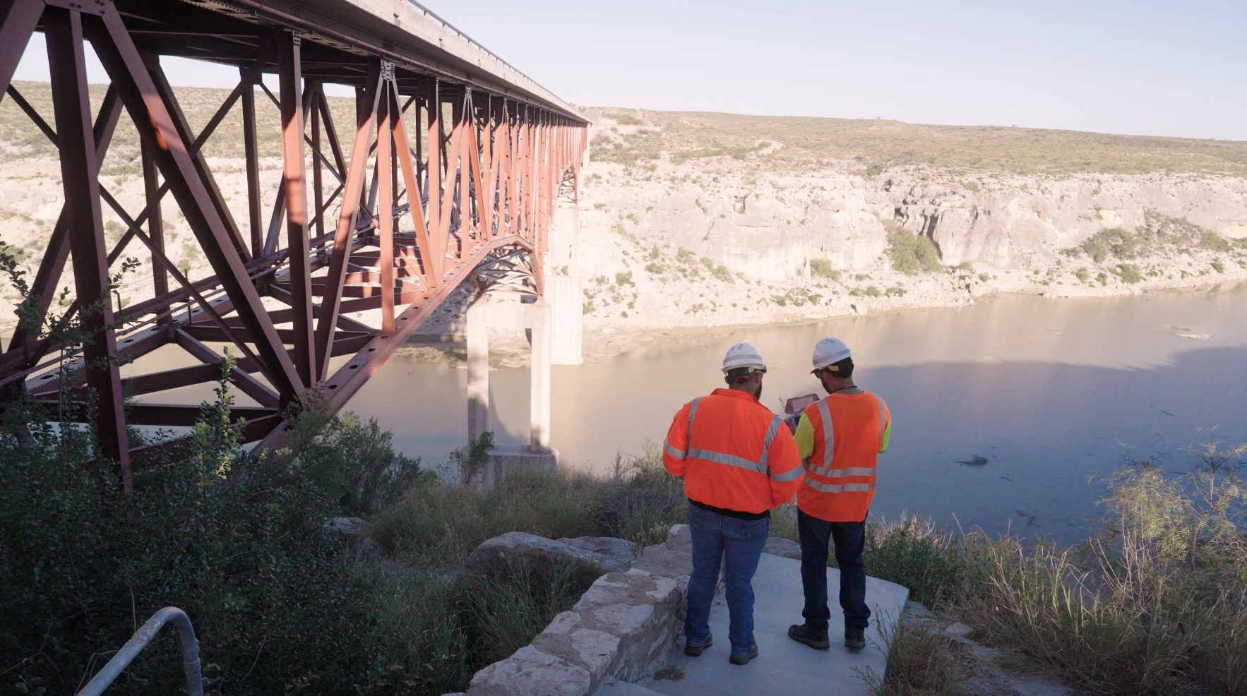worker on site using skydio controller to inspect bridge in background.