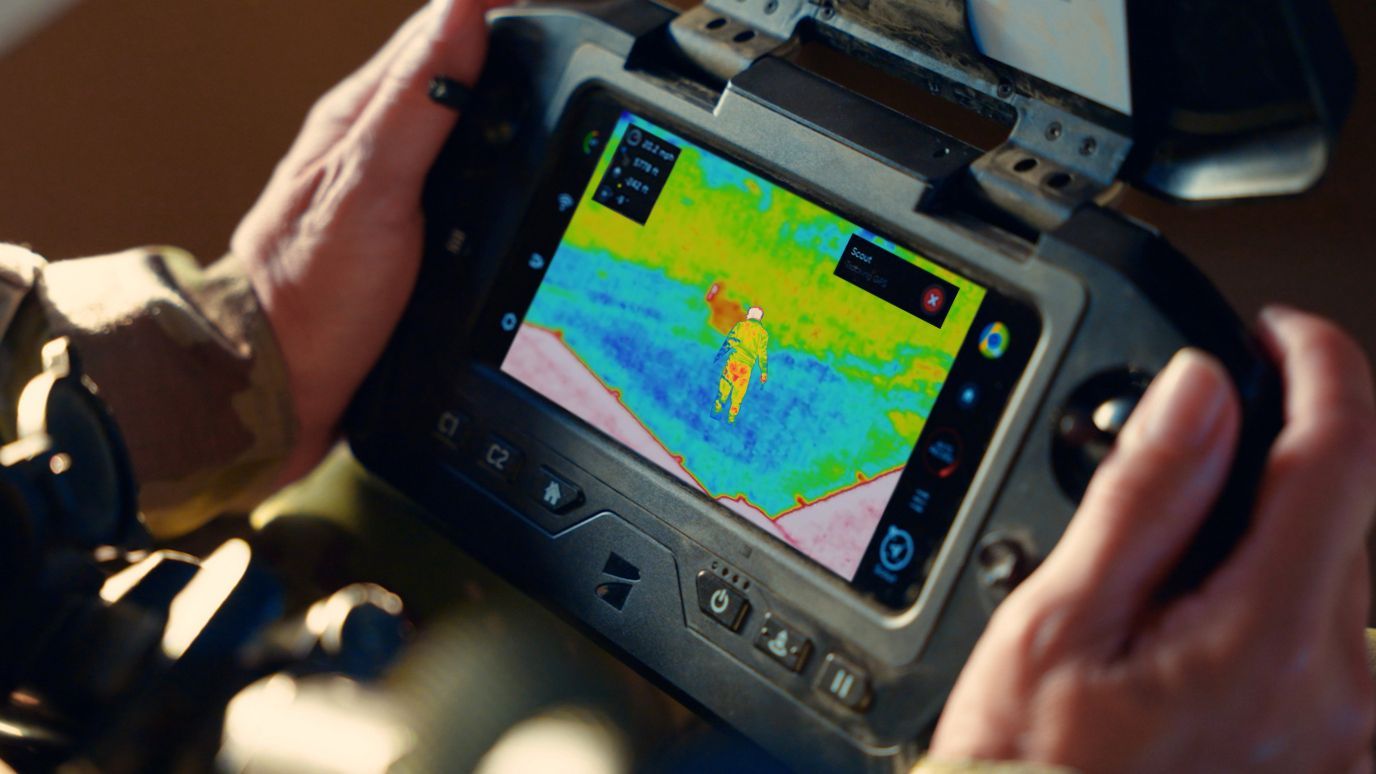 hand holding drone controller watching thermal footage in app