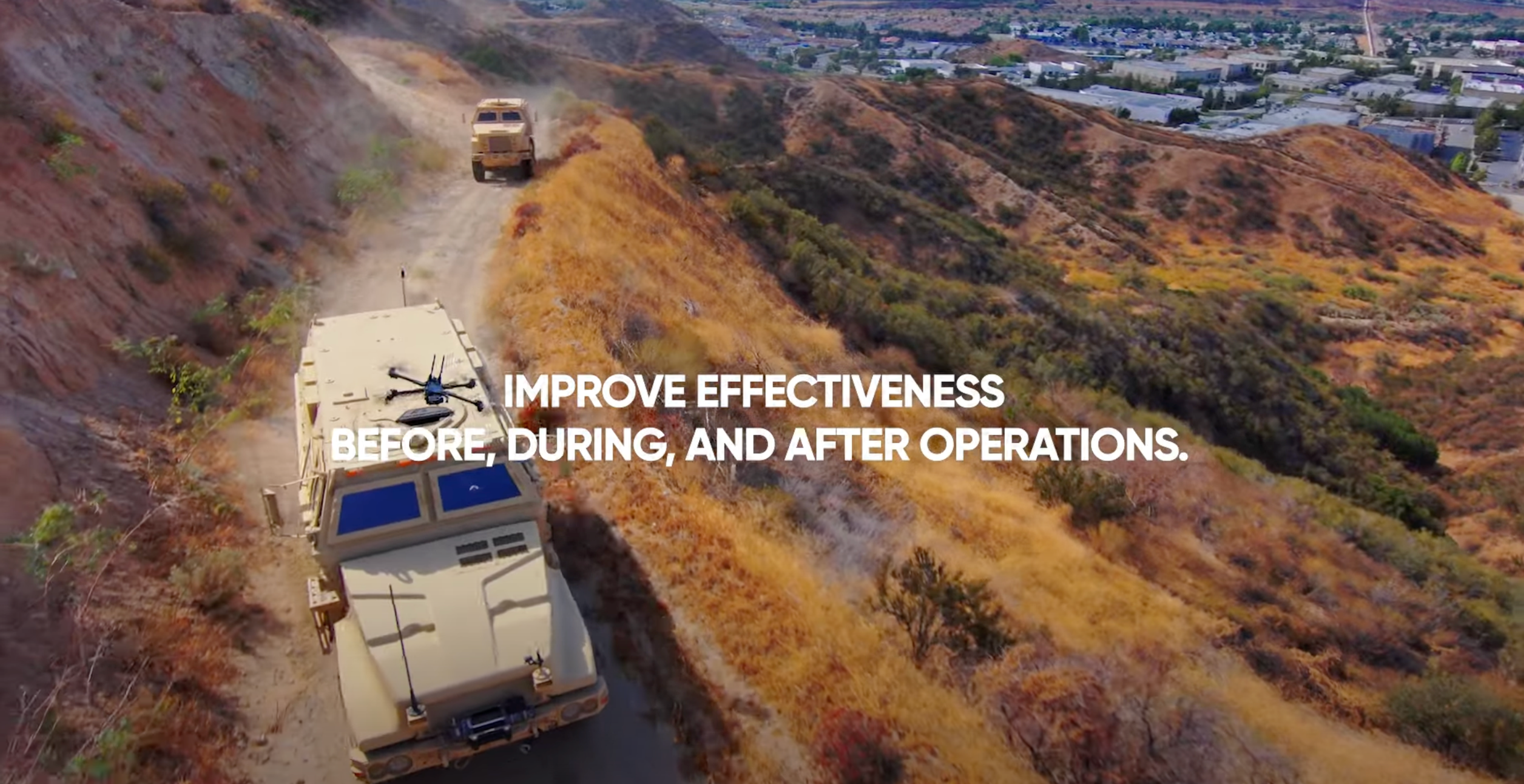 military vehicles on a dirt road with Skydio drone scouting ahead
