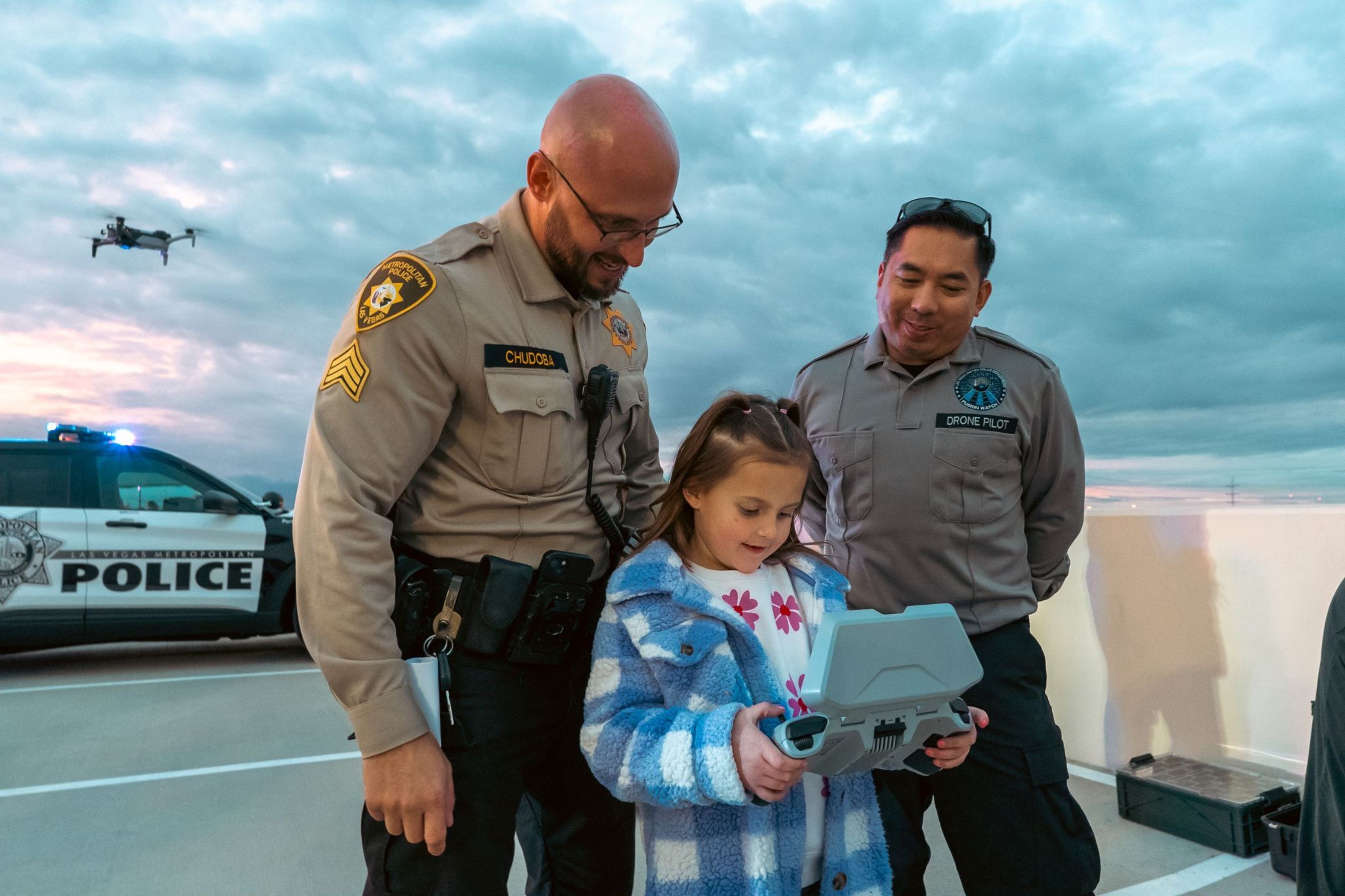 child looking at Skydio live view of Drone on Controller as Las Vegas Metro PD officers look on