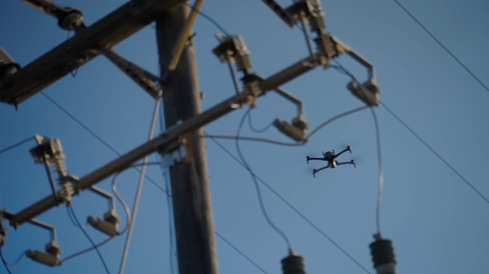Skydio X10 drone pausing at pole to inspecting power line components