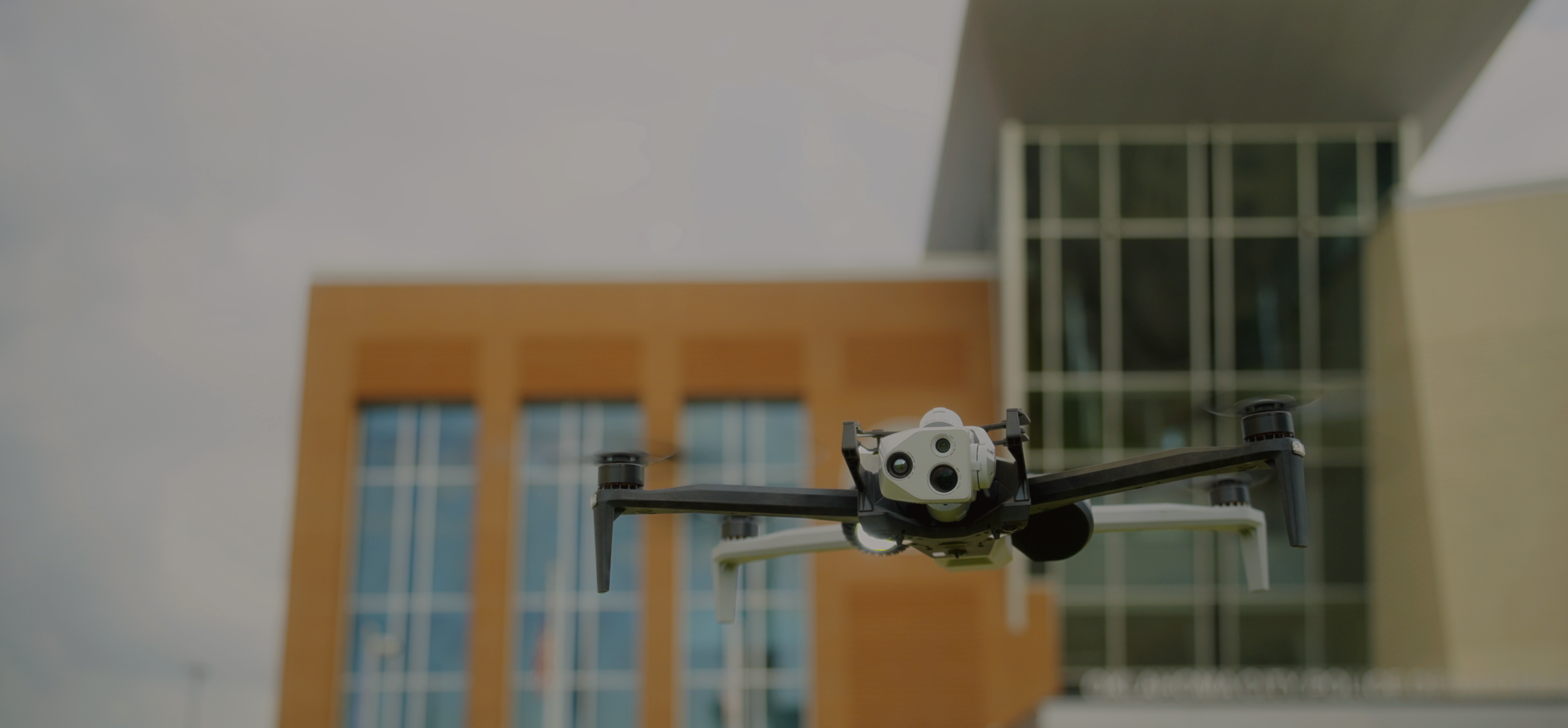 Skydio X10 drone in flight with two tall buildings in the background