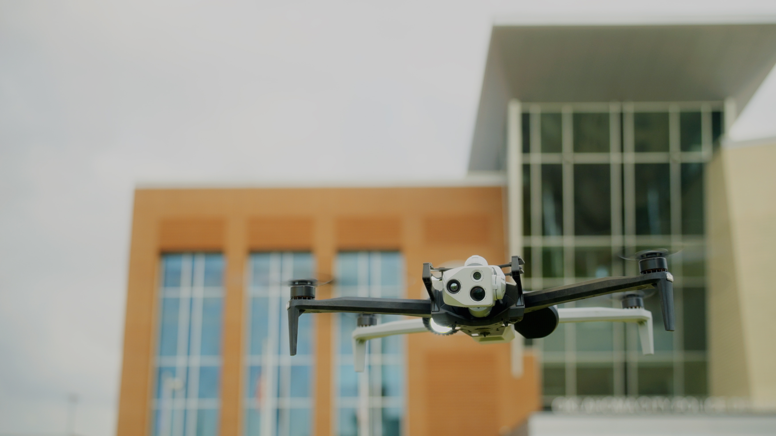 Skydio X10 drone in flight in front of two tall buildings