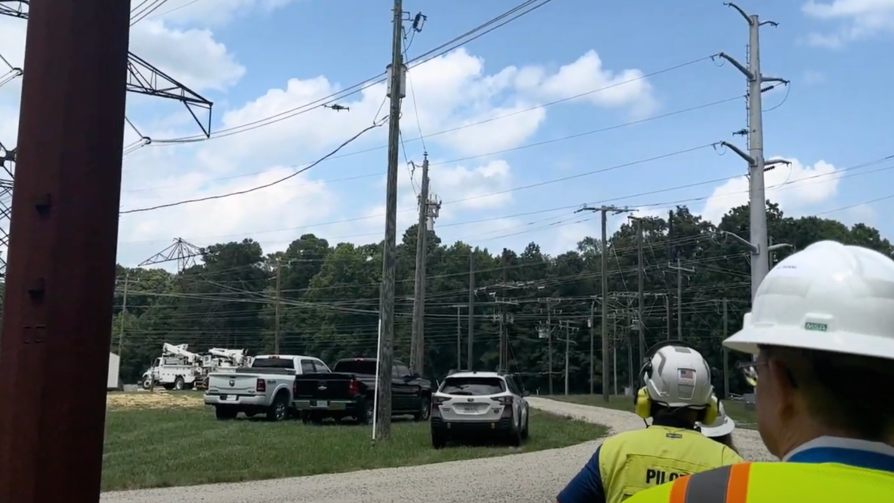 two workers flying a drone around power lines