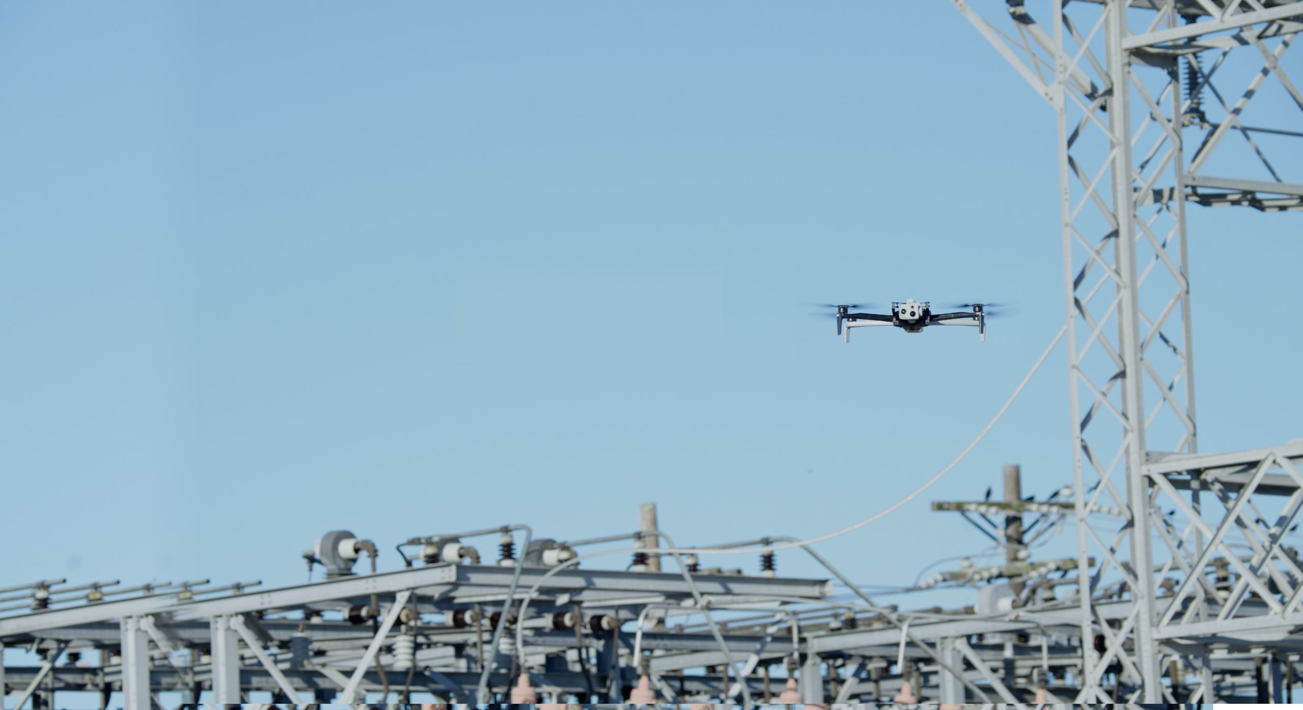 Wide view of a Skydio drone flying in a electrical power substation location