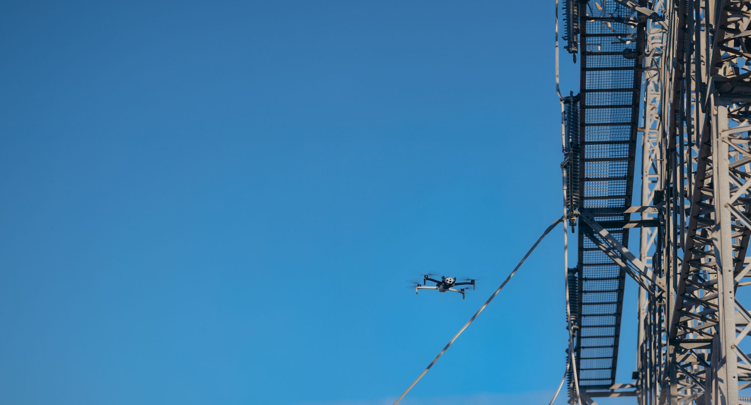 Wide view of Skydio drone flying around a power line