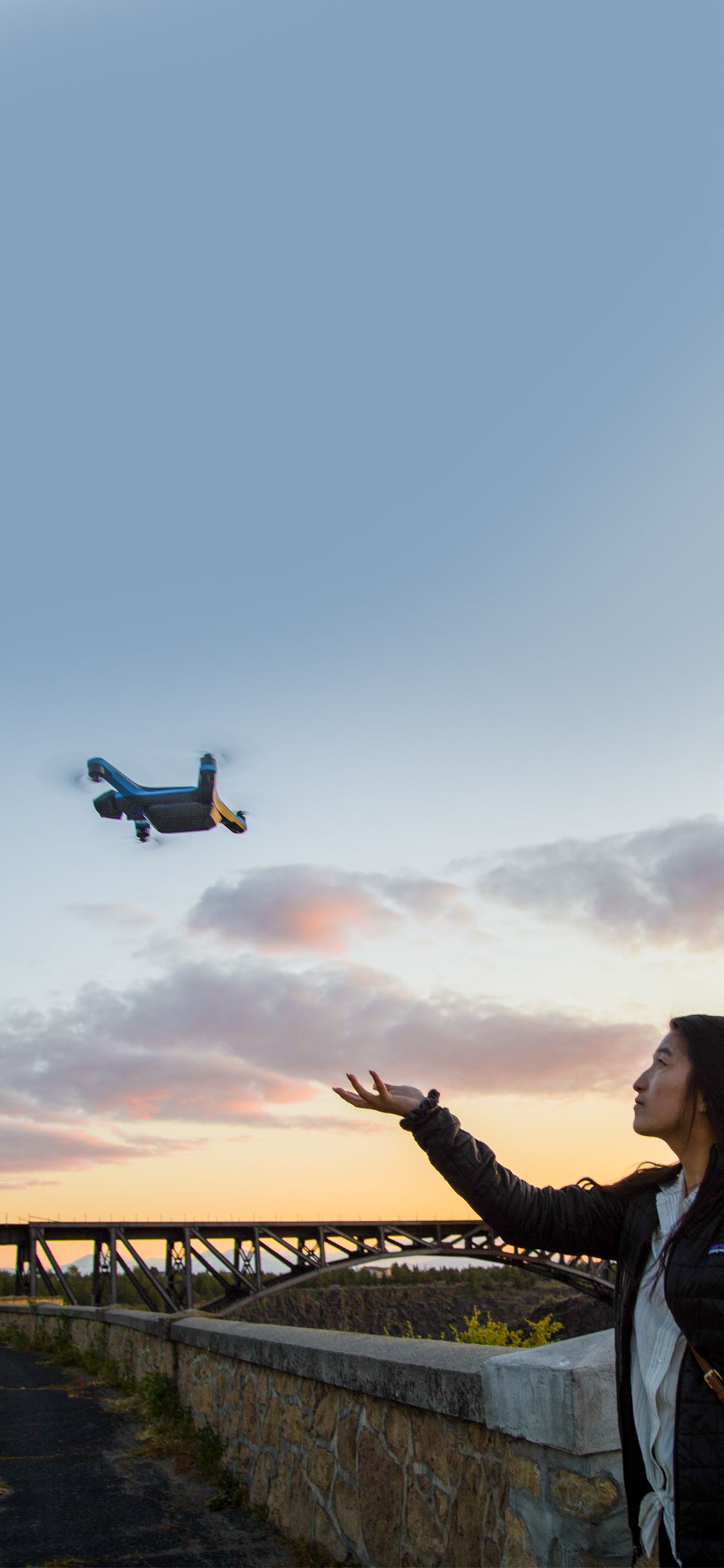 person hand launching skydio 2+ drone with colorful sunset in the background 