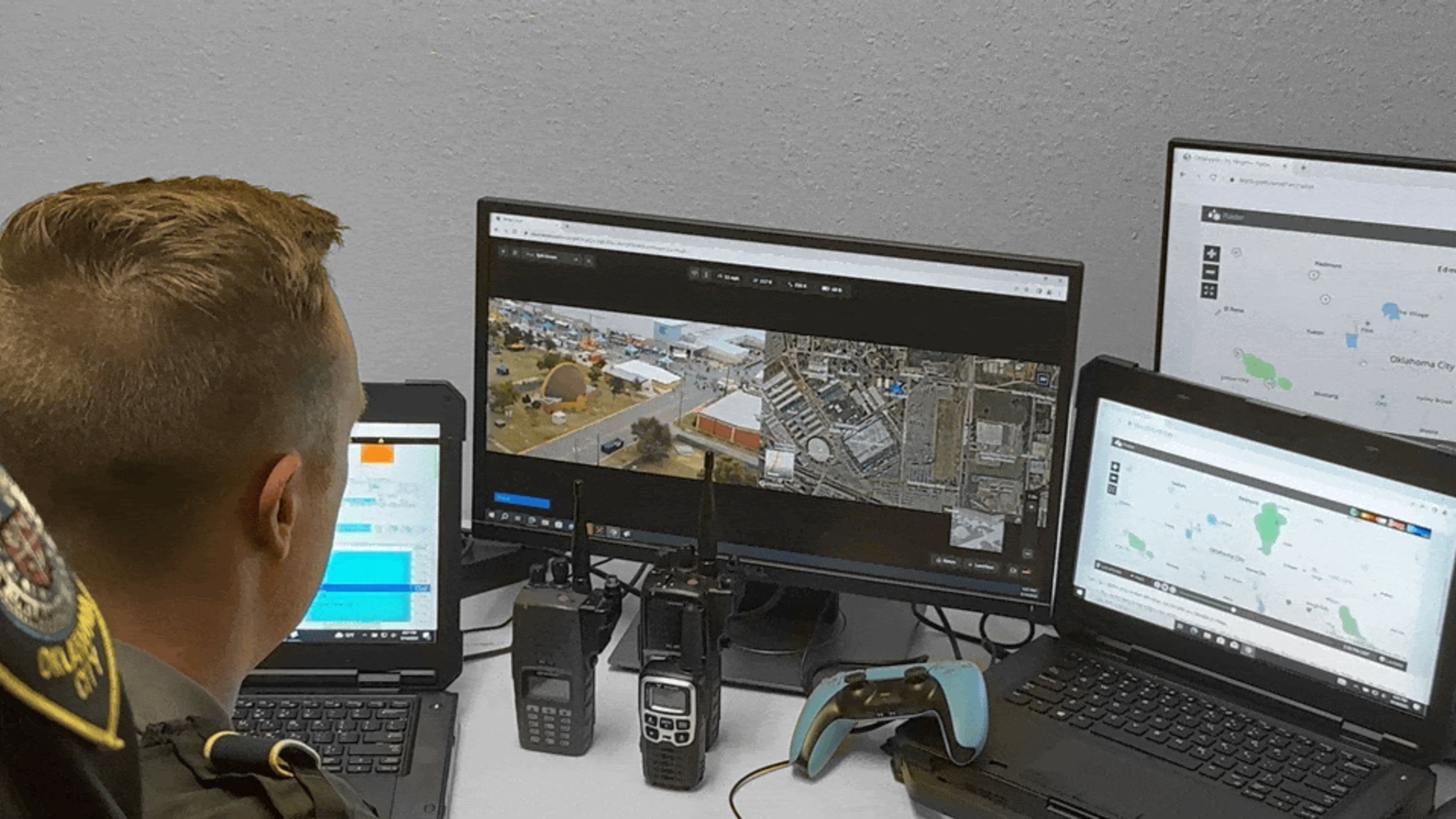 Oklahoma City Police officer sitting at a desk looking at several displays and open laptops with various realtime drone footage and maps