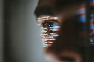 Close-up of an eye reflecting colorful computer code