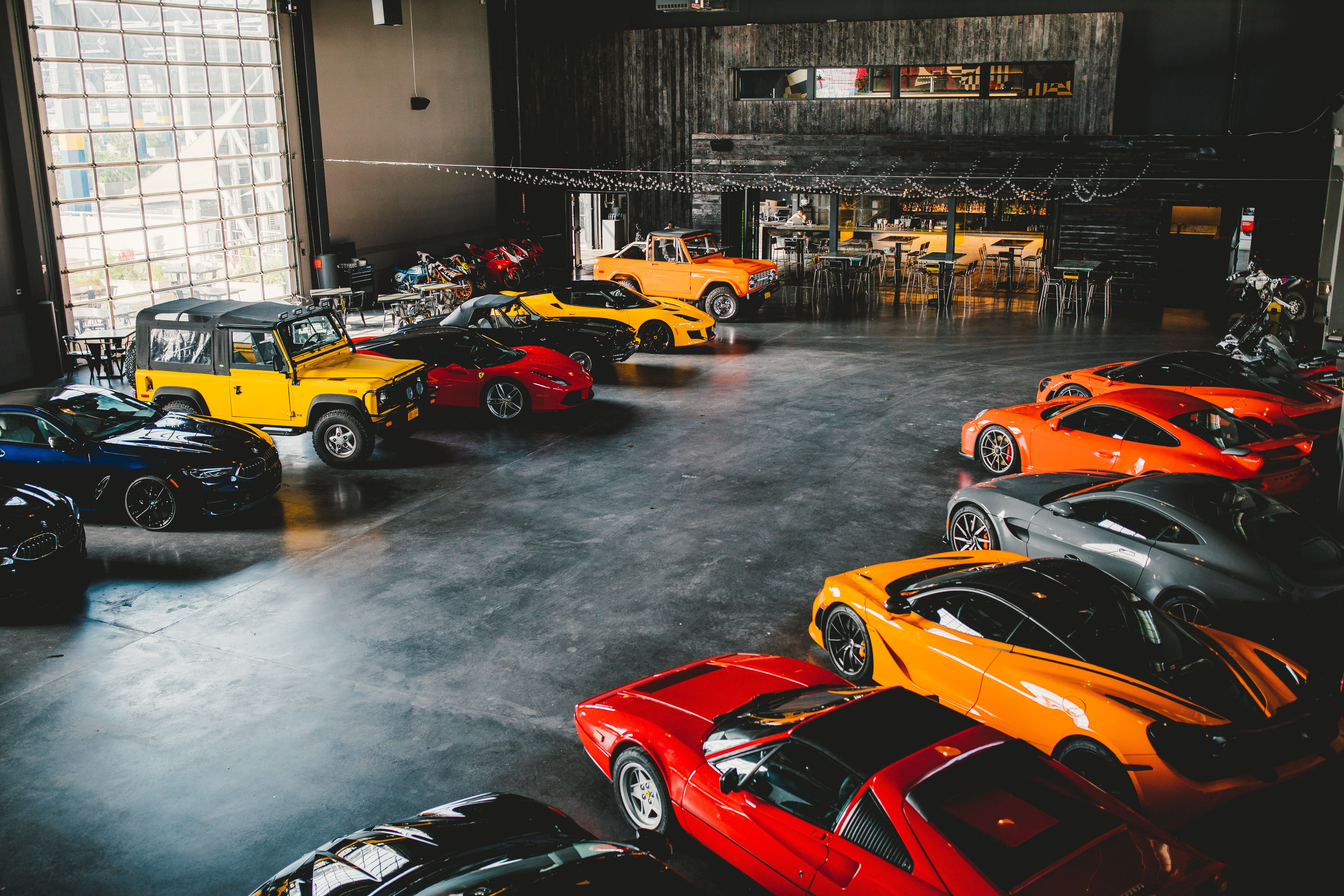 A collection of sports and performance cars in a concrete urban garage.