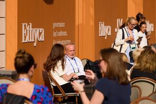 People sitting outside inn cafe chairs with Ethyca branding on an orange wall.