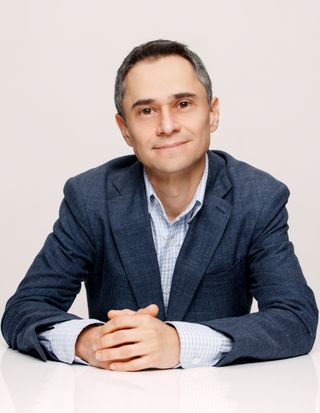A man in a blue shirt sitting at a white table.