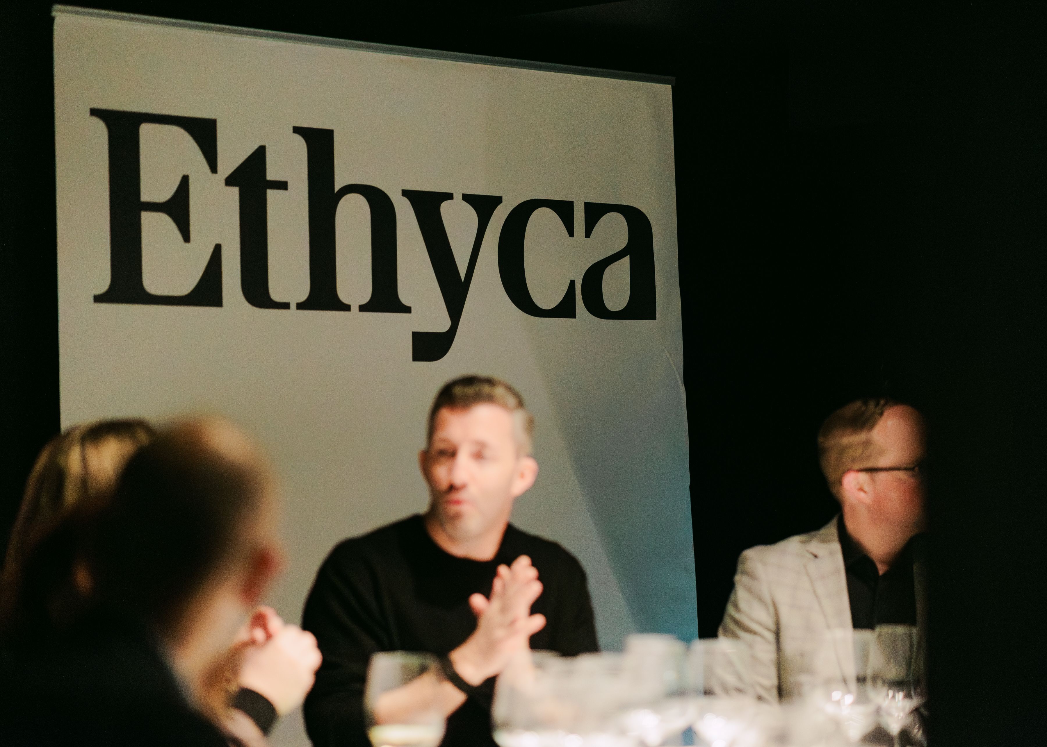 People sitting around a table in front of an Ethyca banner.