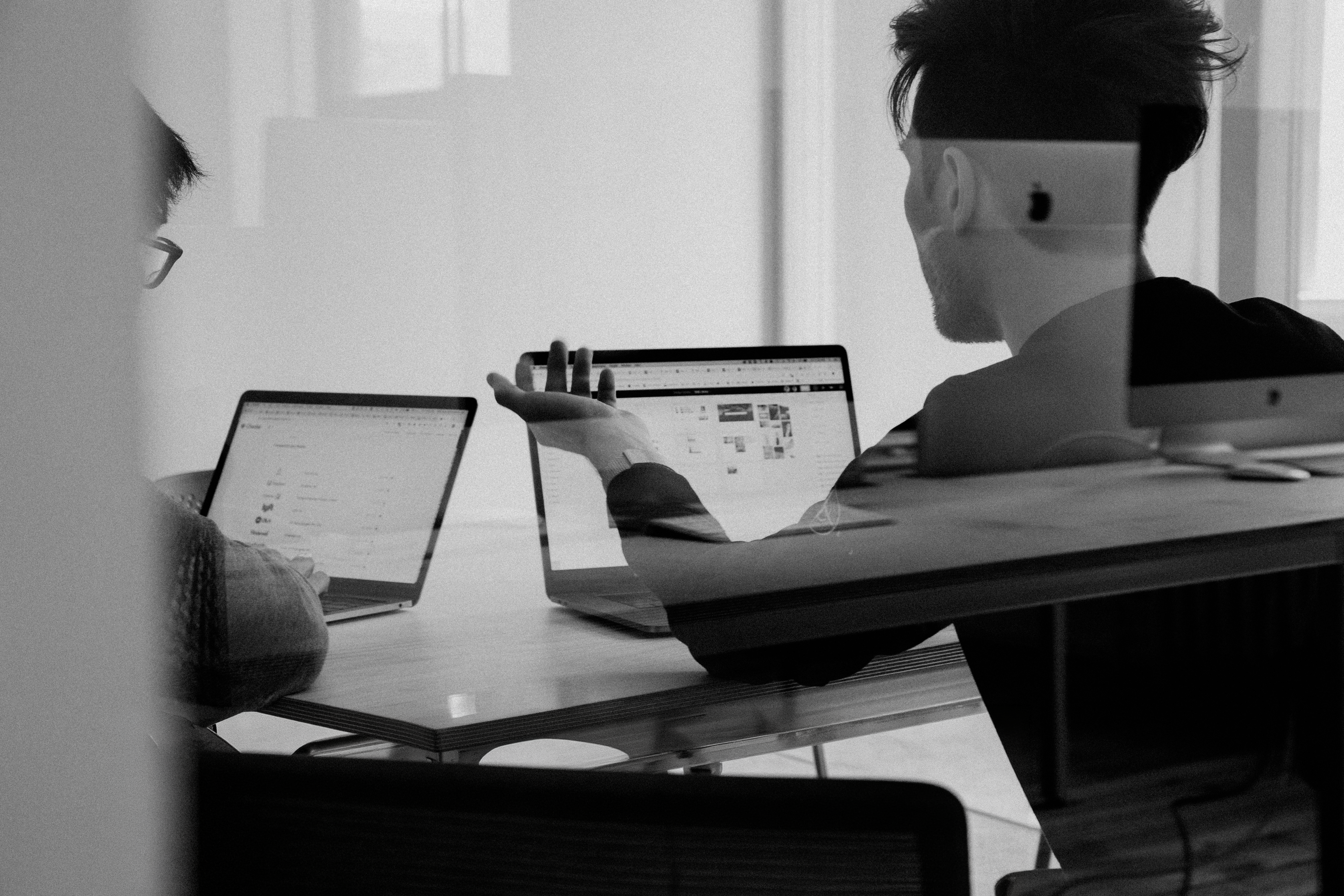 two-men-sitting-at-a-table-working-on-a-laptop