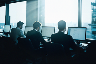 Two businesspeople in suits in a modern office building conference room.