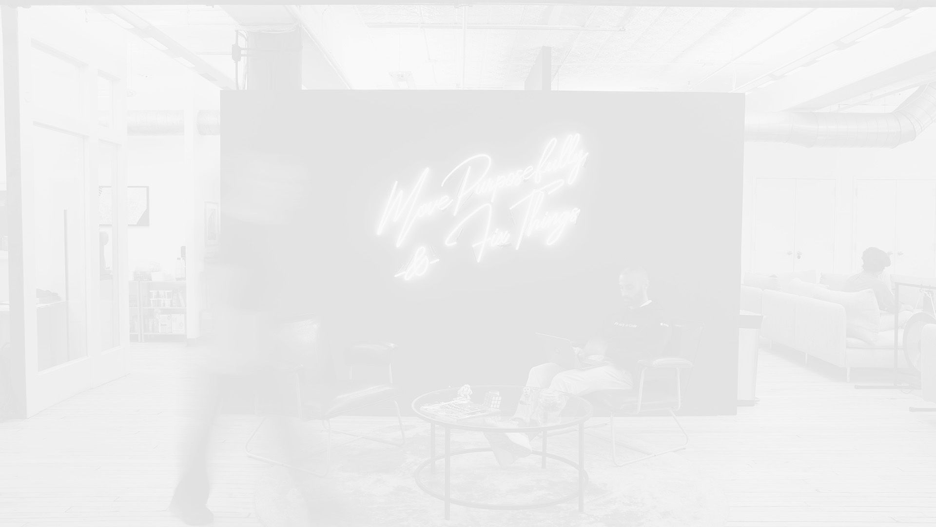 A loft startup office with people walking and working, in black and white.