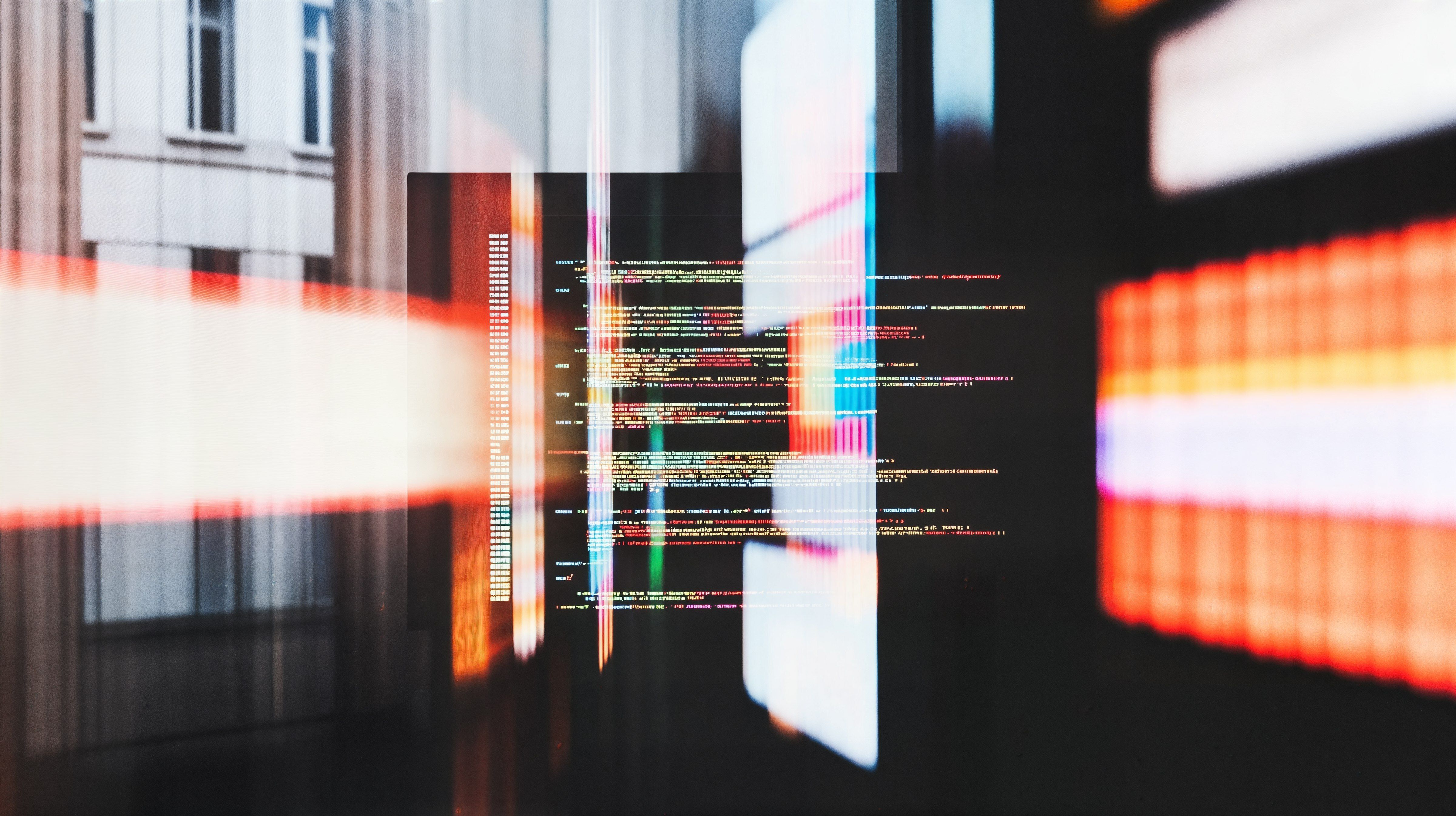 Futuristic overlay of programming code on a blurred urban building with vibrant light streaks, symbolizing technology and innovation