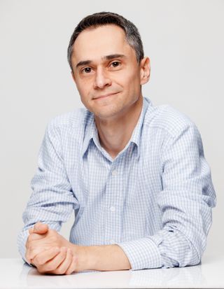 A man in a blue shirt sitting at a white table.