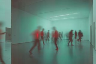 Blurred figures move in a minimalist teal room