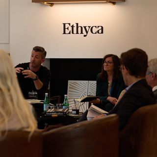 People talking in a circle in front of an Ethyca logo.