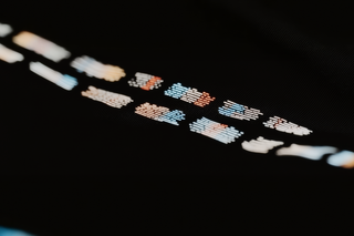 Abstract glowing rectangular patterns in white, orange, and blue on a dark background, evoking a futuristic and tech-inspired aesthetic.