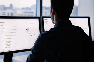 Man sitting in front of computer screens working in Fides.