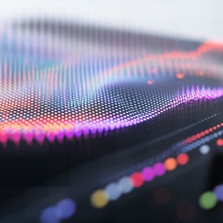 Vibrant digital wave visualization with multicolored dots on a dark surface, evoking futuristic data or sound analysis