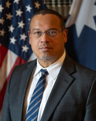 Attorney General Keith Ellison in front of the American and Minnesota state flags.