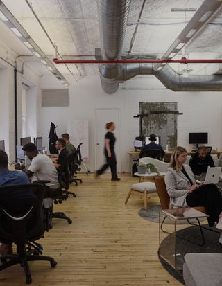 A brightly lit studio with computers on the wall and people working with motion blur