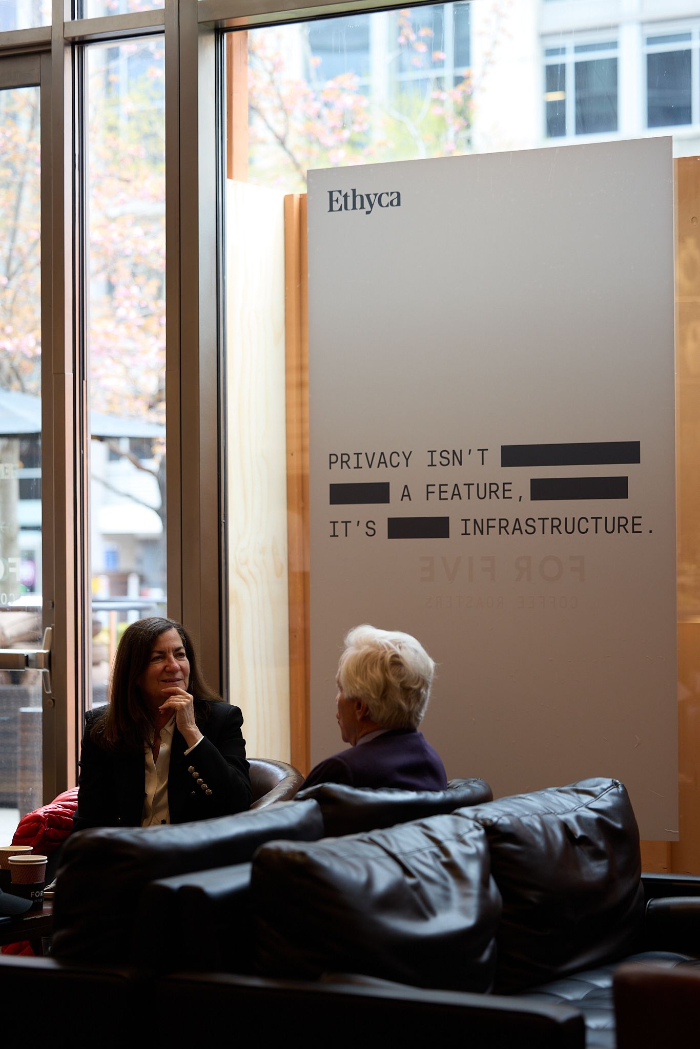 Ethyca poster on the window with two people talking.